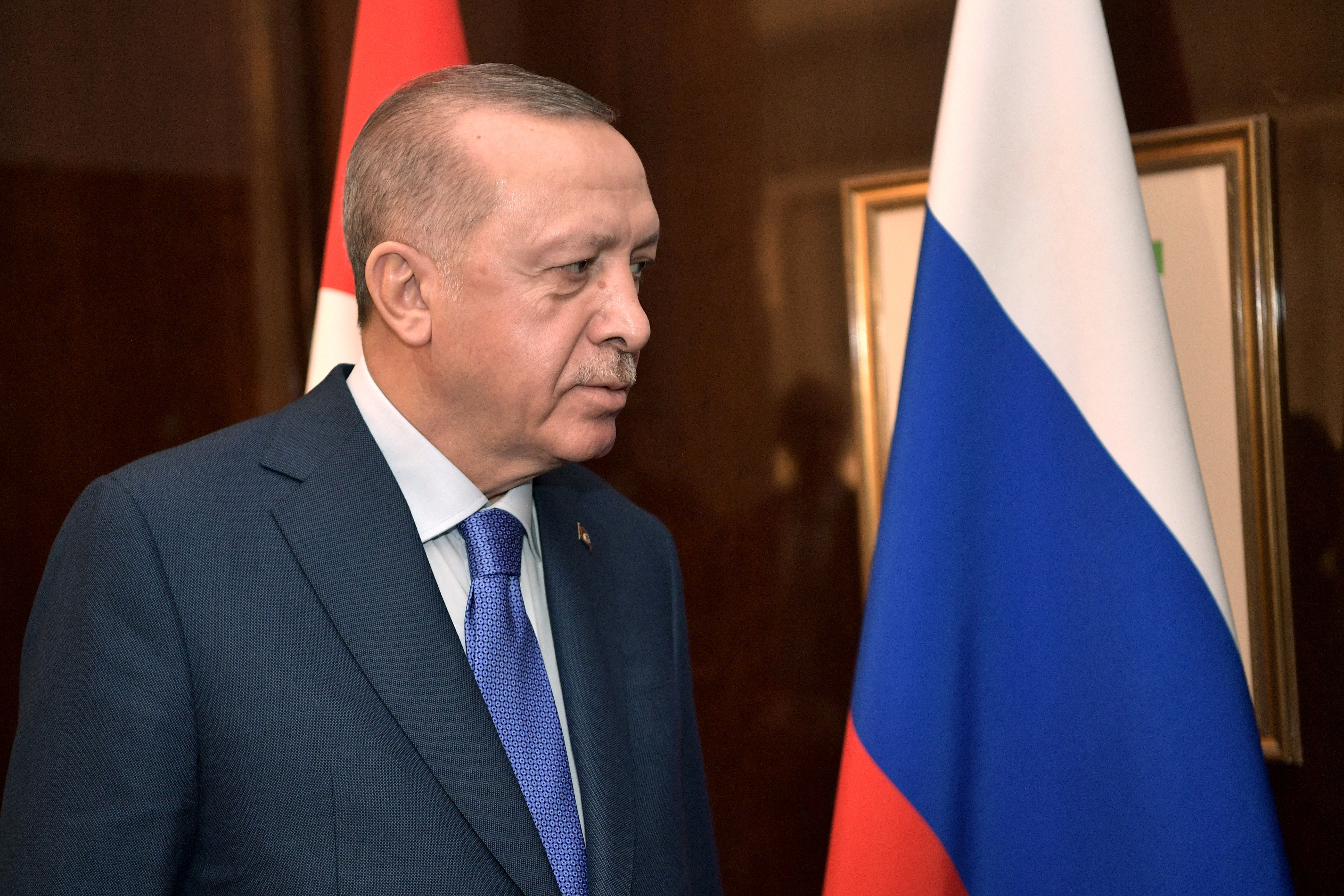 Prezydent Turcji Recep Tayyip Erdogan obok flagi Rosji, omawiający rozmowy pokojowe z Ukrainą.