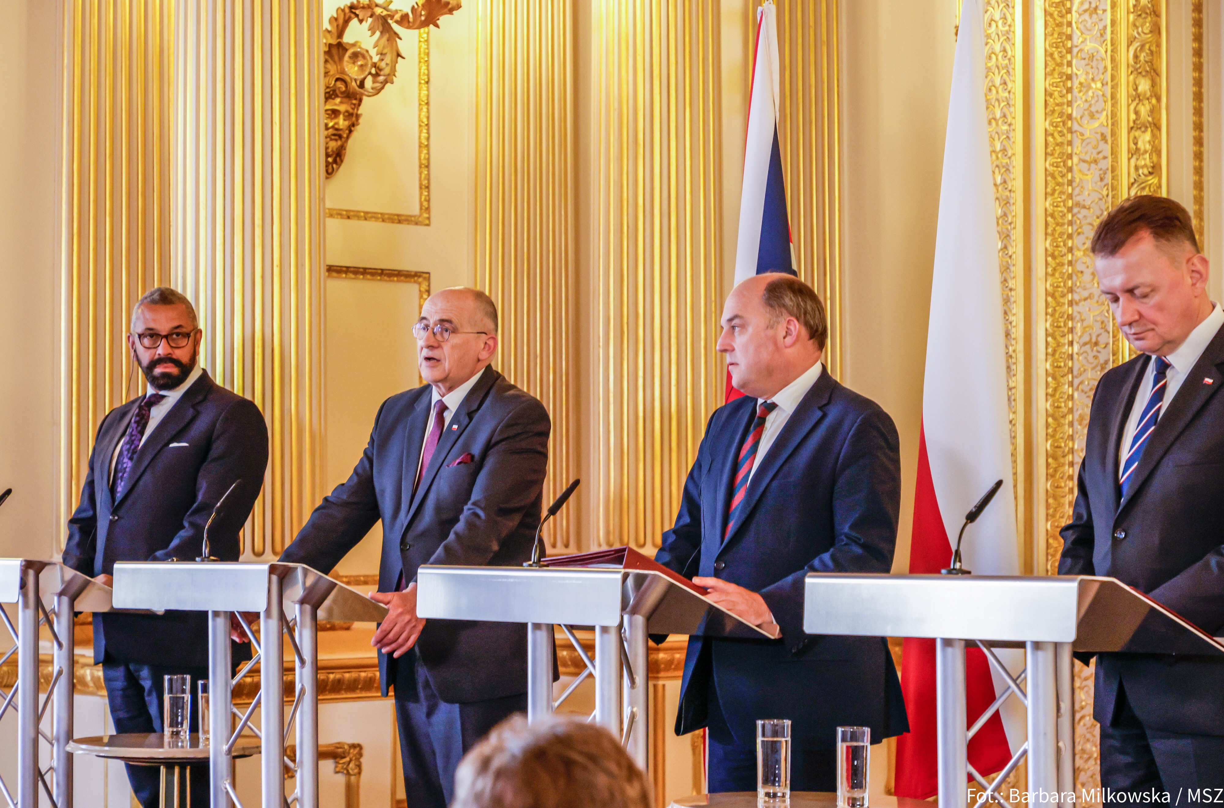 Mariusz Błaszczak w garniturze z krawatem podczas konferencji prasowej.