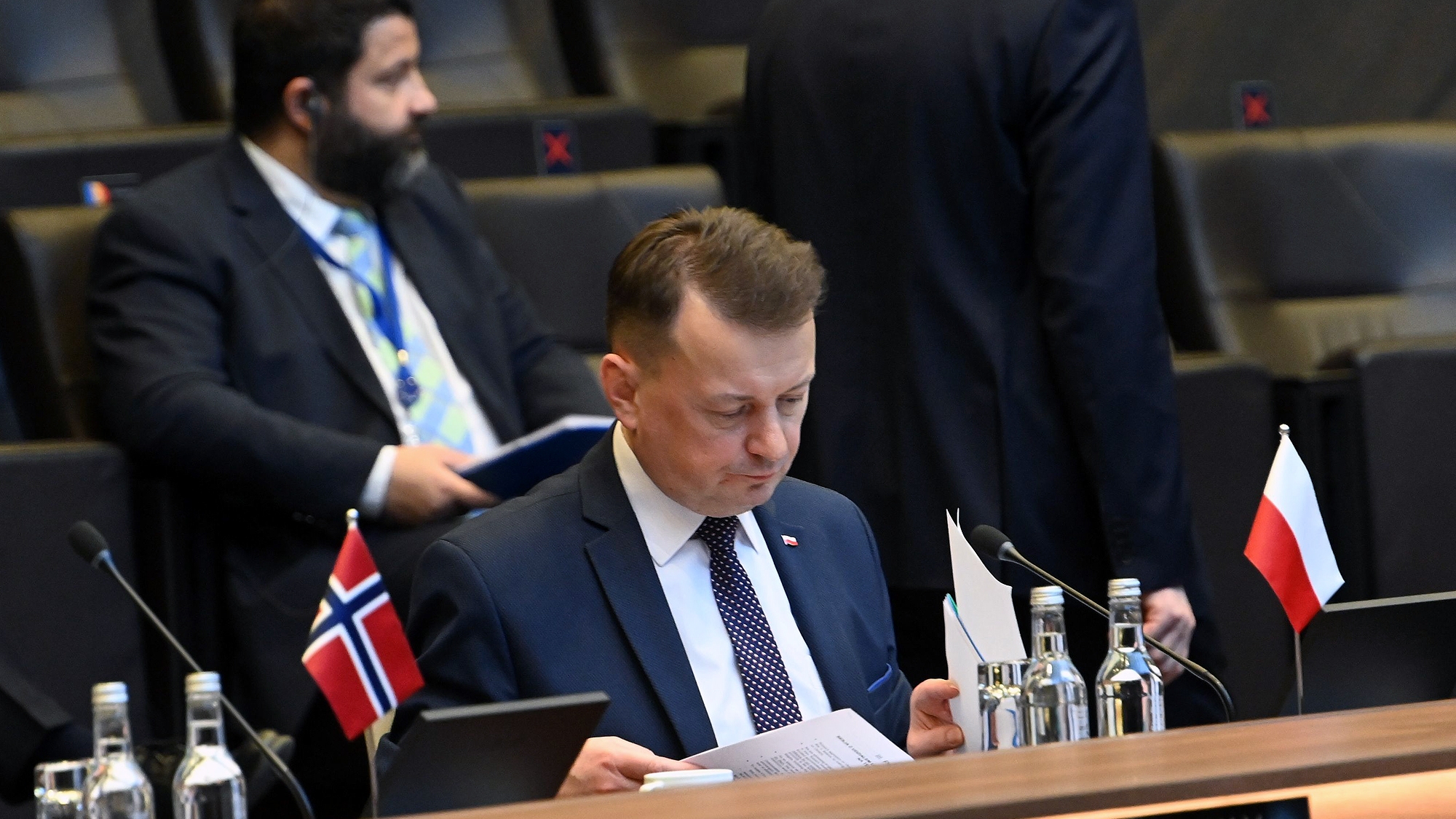 Mariusz Błaszczak podczas posiedzenia, na stole polska flaga.