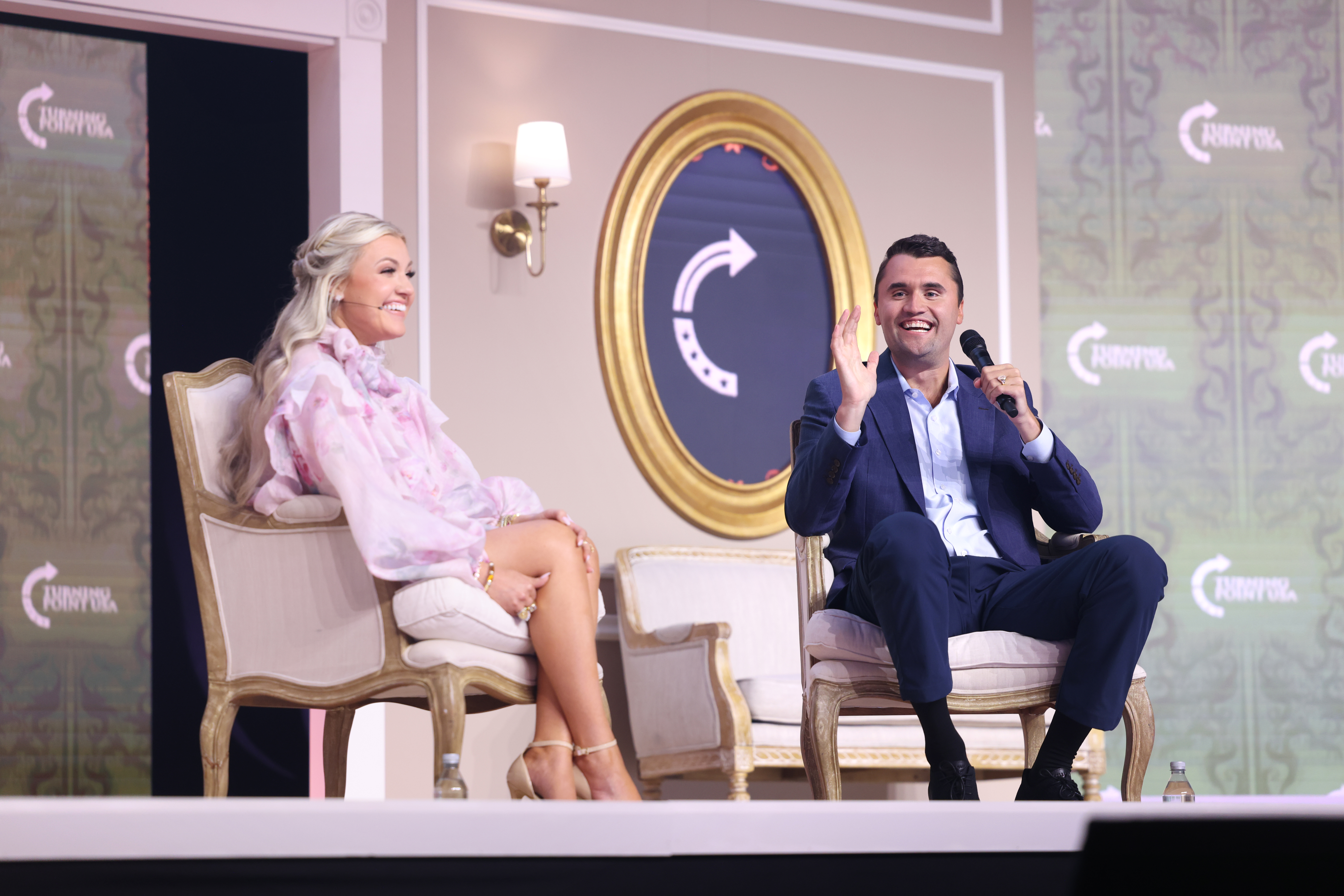 Charlie Kirk podczas przemówienia w Utah, siedzi na krześle z mikrofonem.