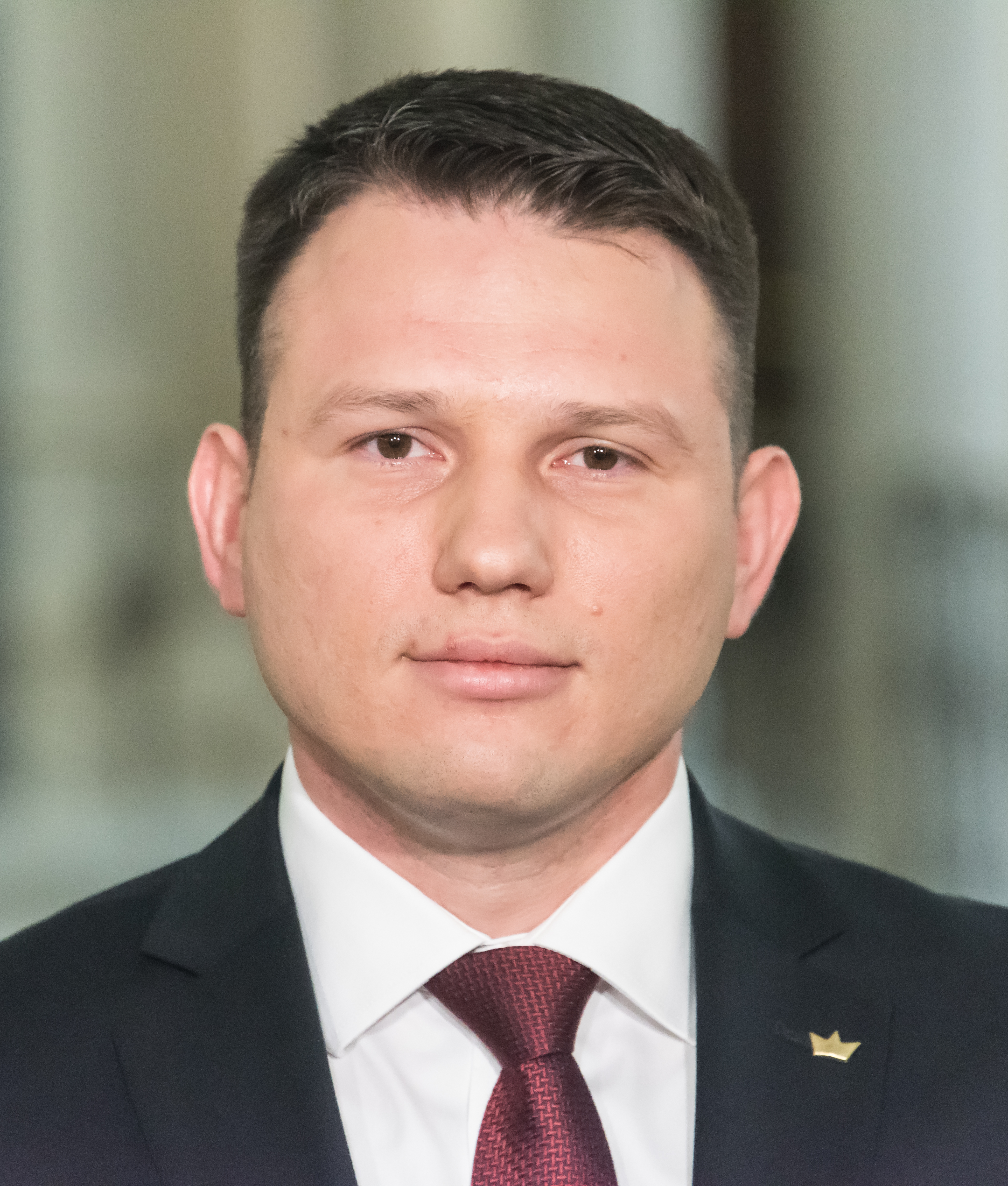 Sławomir Mentzen, lider Konfederacji, w garniturze i krawacie, analizuje wypowiedzi PiS.