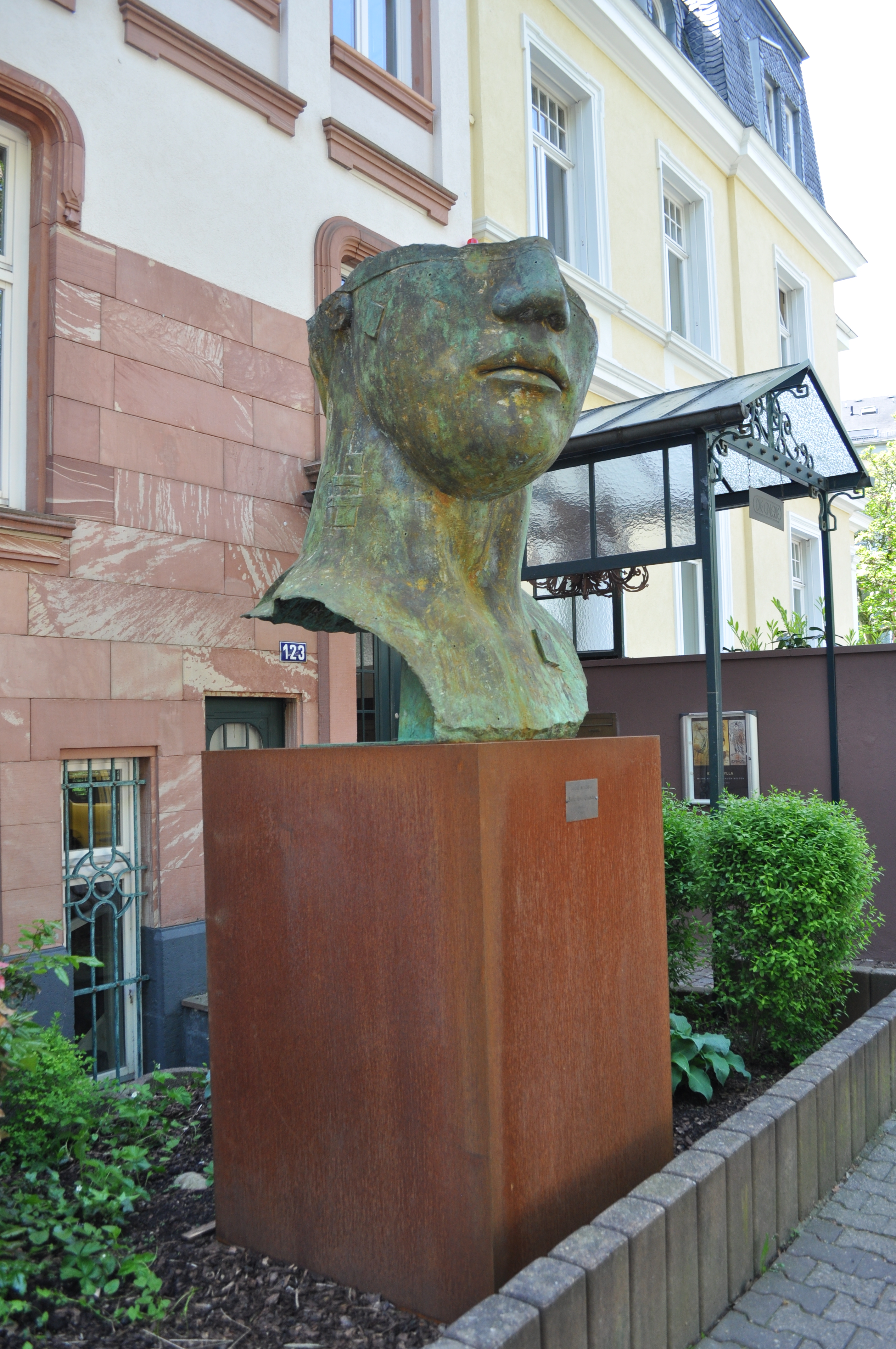 Monumentalna rzeźba "Tindaro" Igora Mitoraja na rustykalnym postumencie, symbol inwestycji w sztukę.