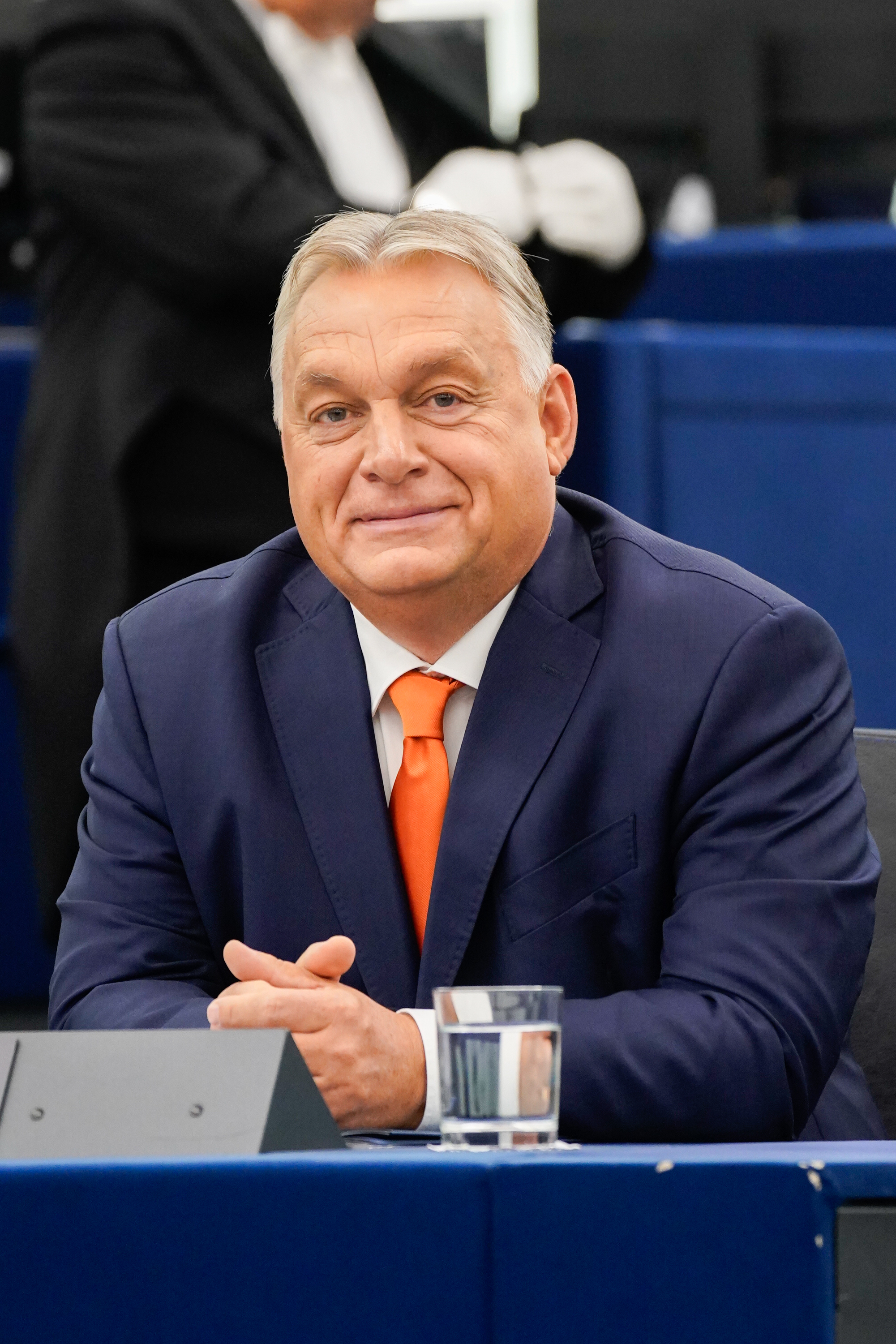 Viktor Orban, premier Węgier, w garniturze i pomarańczowym krawacie, siedzi przy stole.