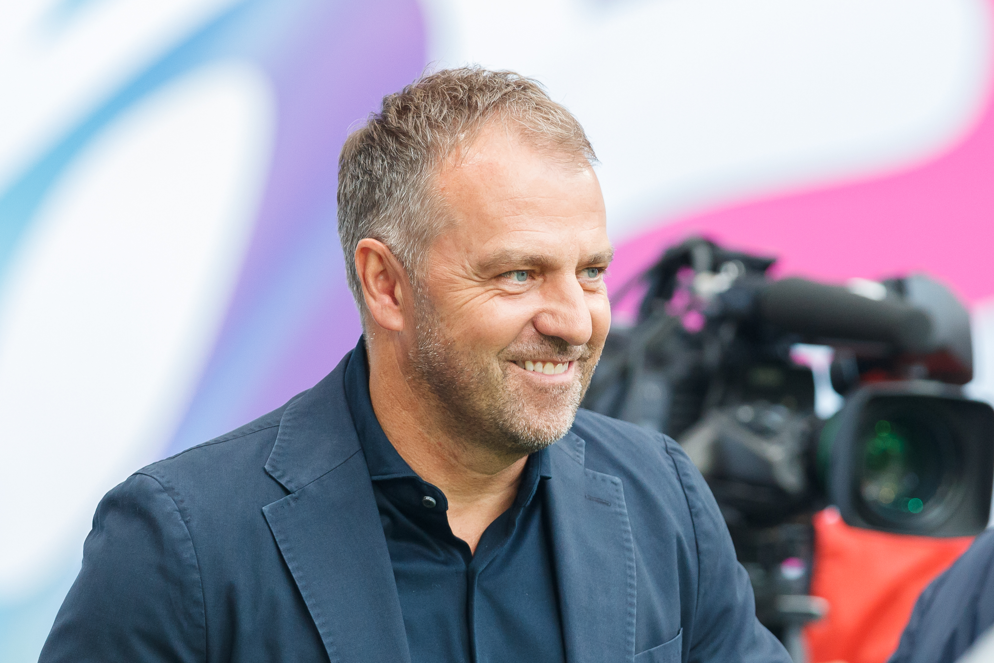 Hans-Dieter Flick, trener Barcelony, podczas konferencji prasowej, z uśmiechem na twarzy.