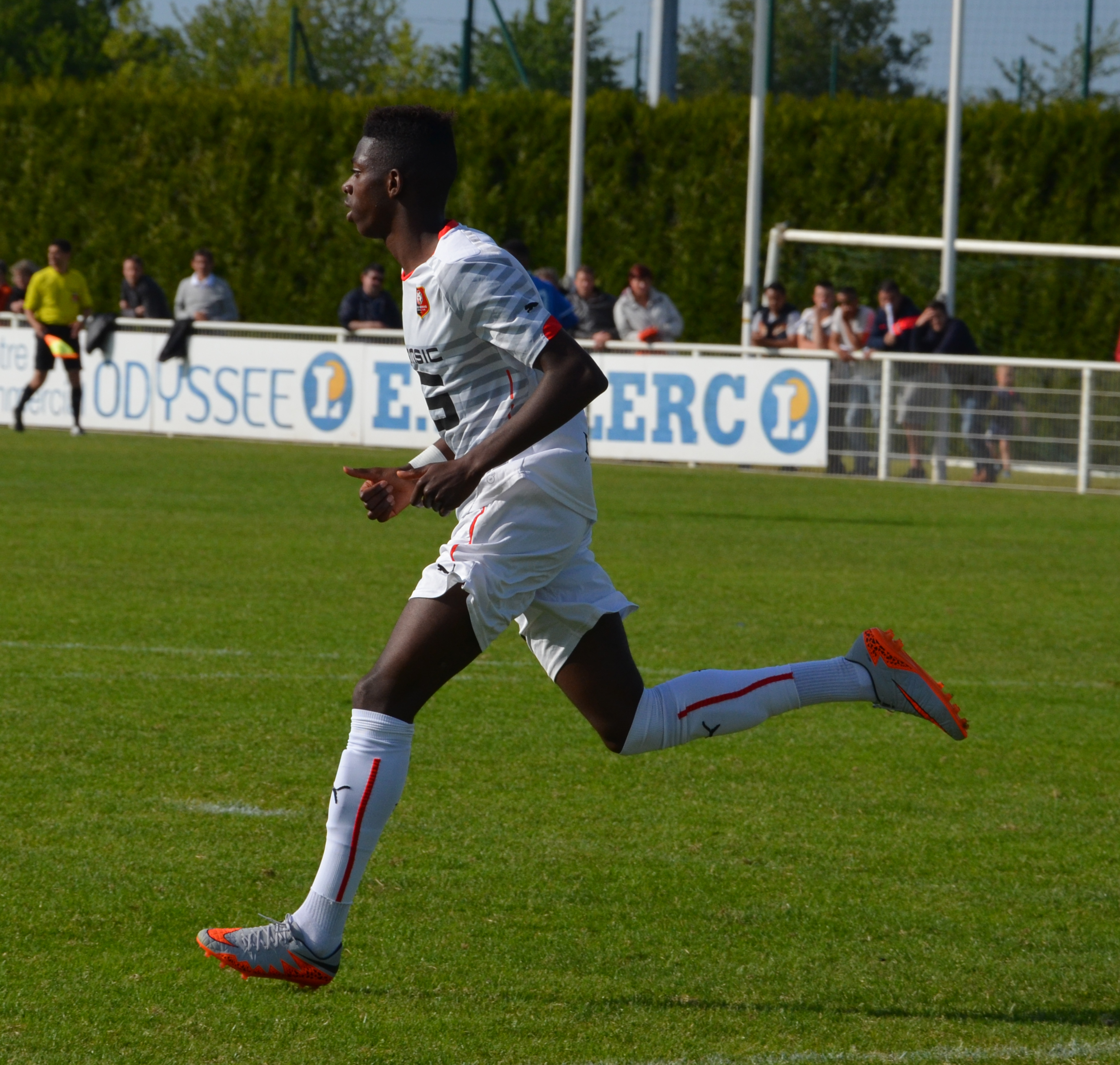 Ousmane Dembele bie po boisku w białej koszulce i białych spodenkach, grając w piłkę nożną.