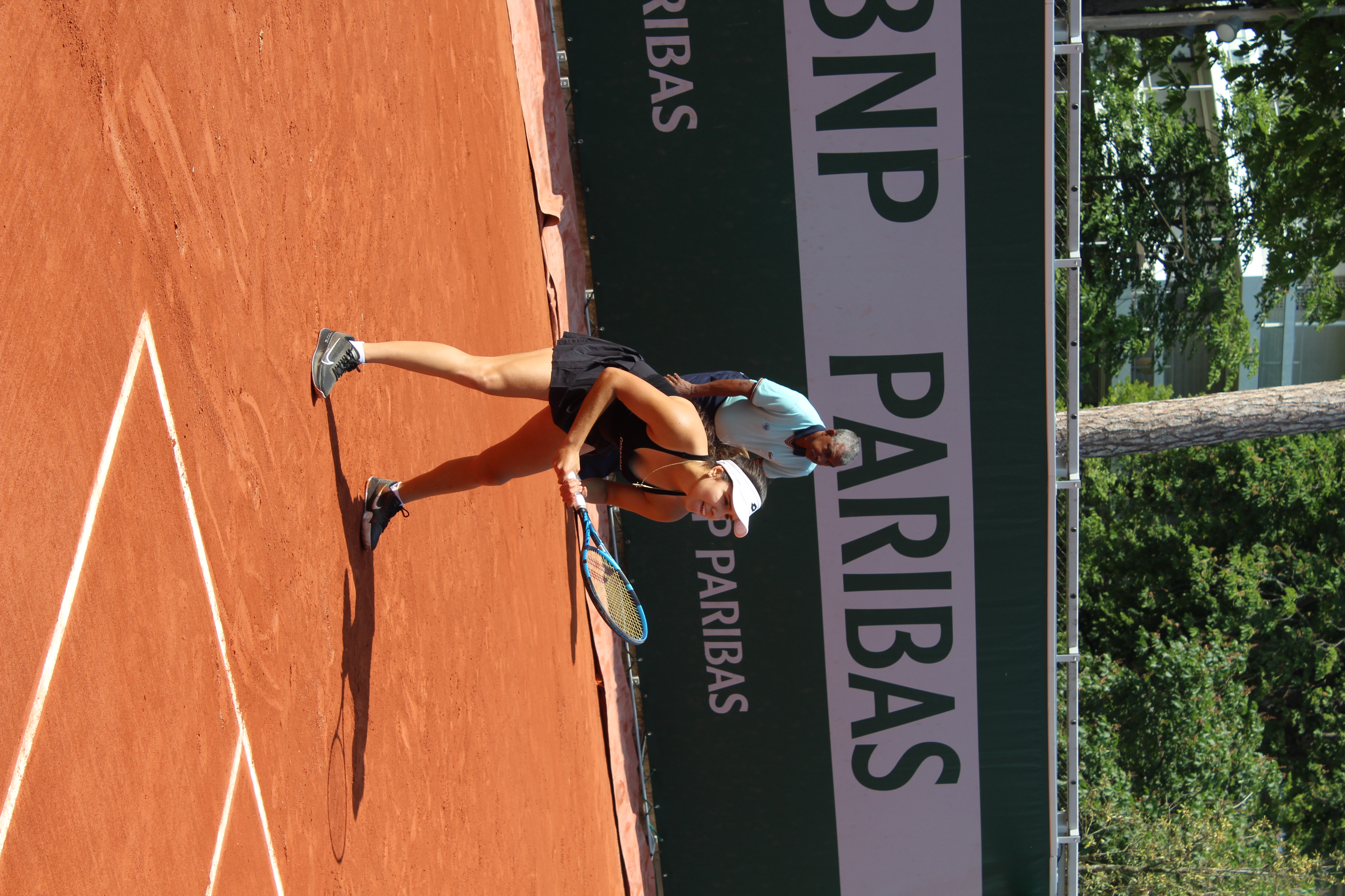 Camila Osorio na korcie tenisowym, gotowa do uderzenia, w tle logo BNP Paribas.