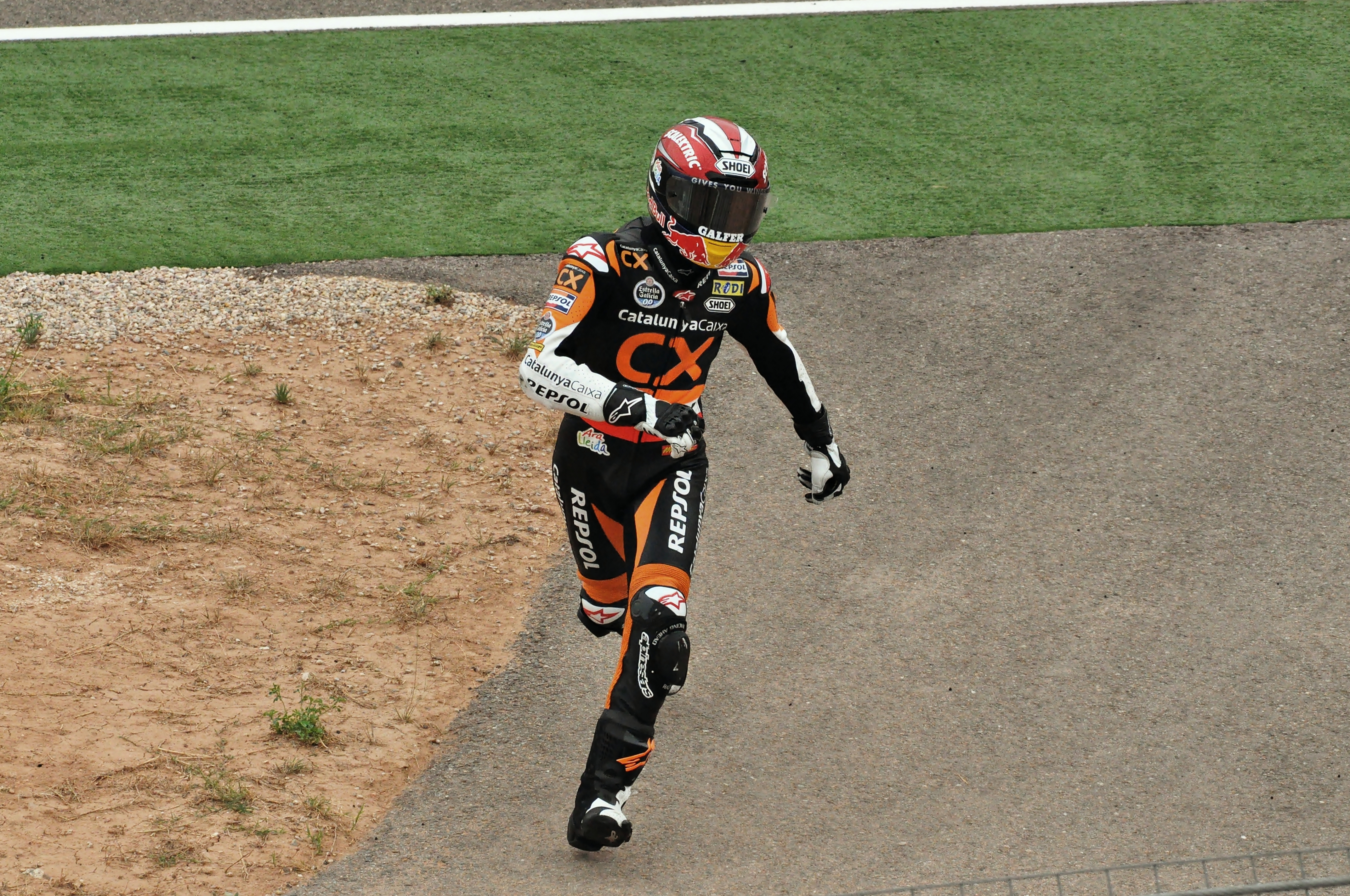 Marc Marquez w kombinezonie Repsol biegnie na torze MotoGP po wypadku, symbolizując jego walkę o powrót.