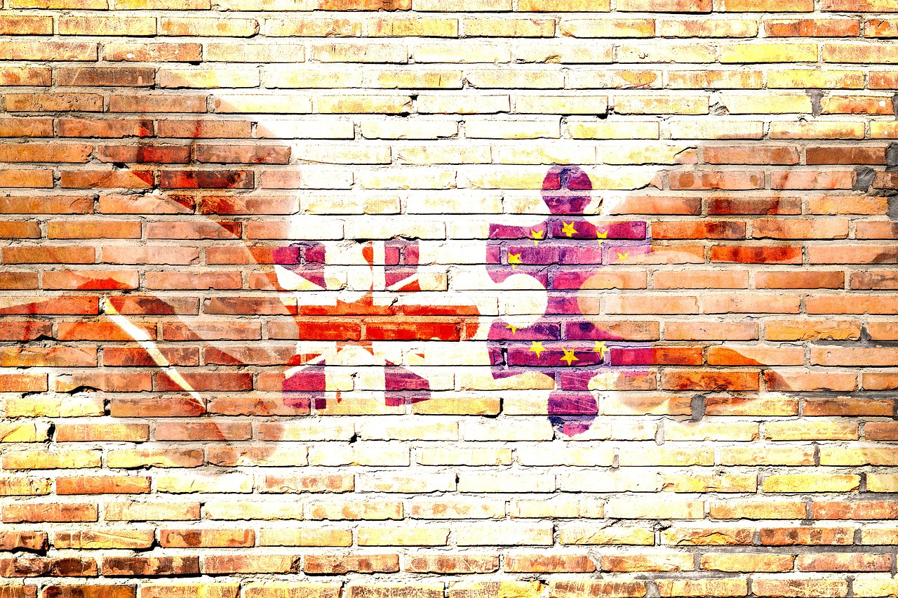 Dwie połówki puzzli z flagą USA i UE na ceglanej ścianie.