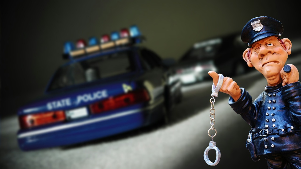 Figurka policjanta trzymająca kajdanki, z radiowozem w tle, ilustrująca podwójną ucieczkę w Warszawie.