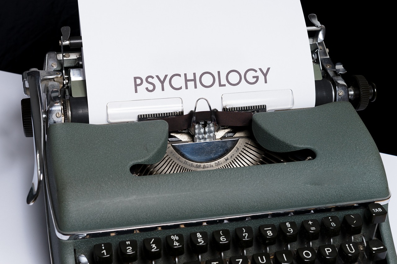 Maszyna do pisania z napisem PSYCHOLOGY na papierze, symbolizująca psychikę.