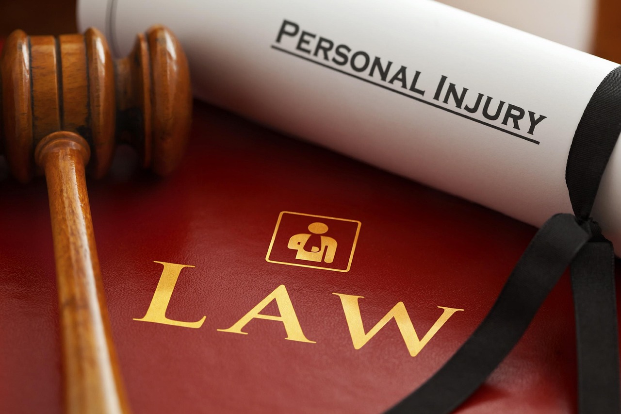 Młotek sędziowski i dokumenty "LAW" oraz "PERSONAL INJURY" symbolizujące proces sądowy w sprawie potrącenia.
