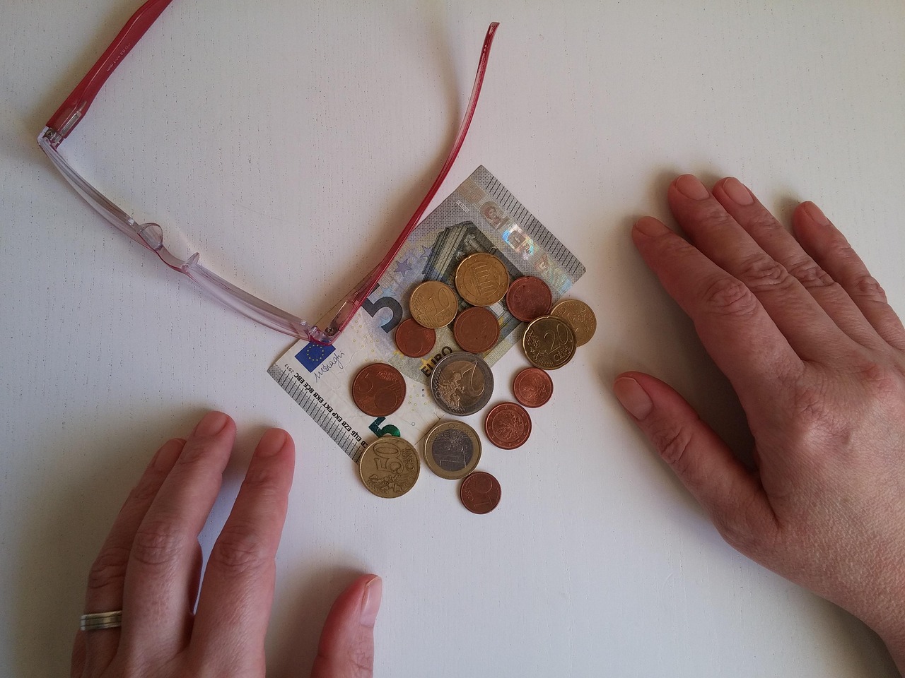 Okulary i monety euro na banknocie, ilustrujące limity dorabiania na wcześniejszej emeryturze.