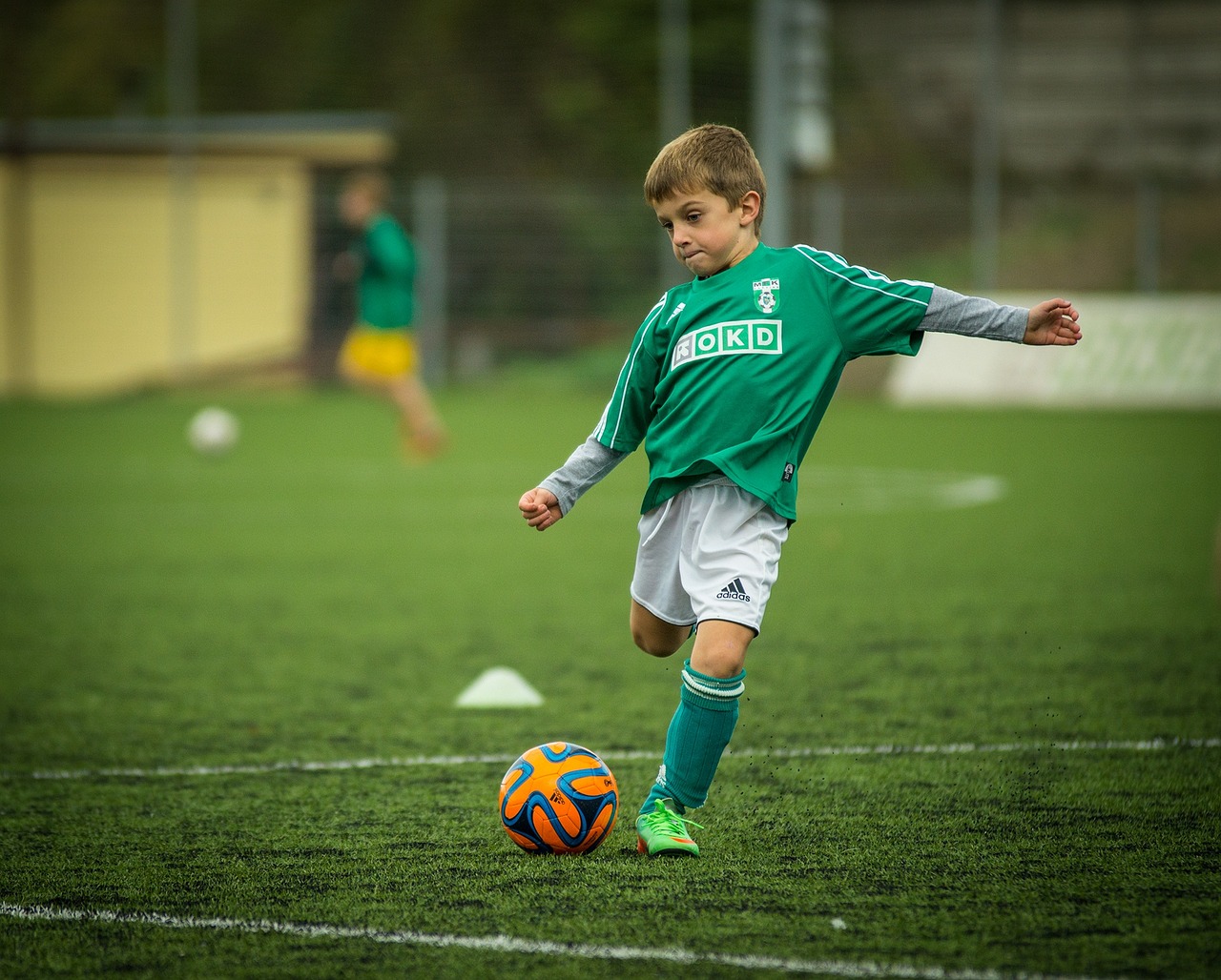Młody piłkarz w zielonej koszulce trenuje na boisku, przygotowując się do meczu el. MŚ 2026.