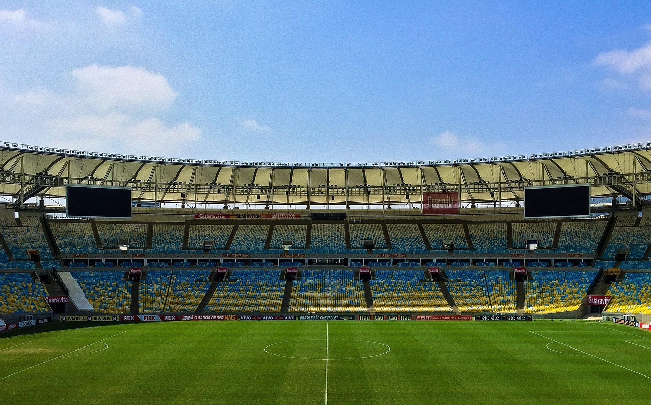 Puste trybuny stadionu piłkarskiego z widokiem na murawę, gotowe na mecz Dania vs Grecja.