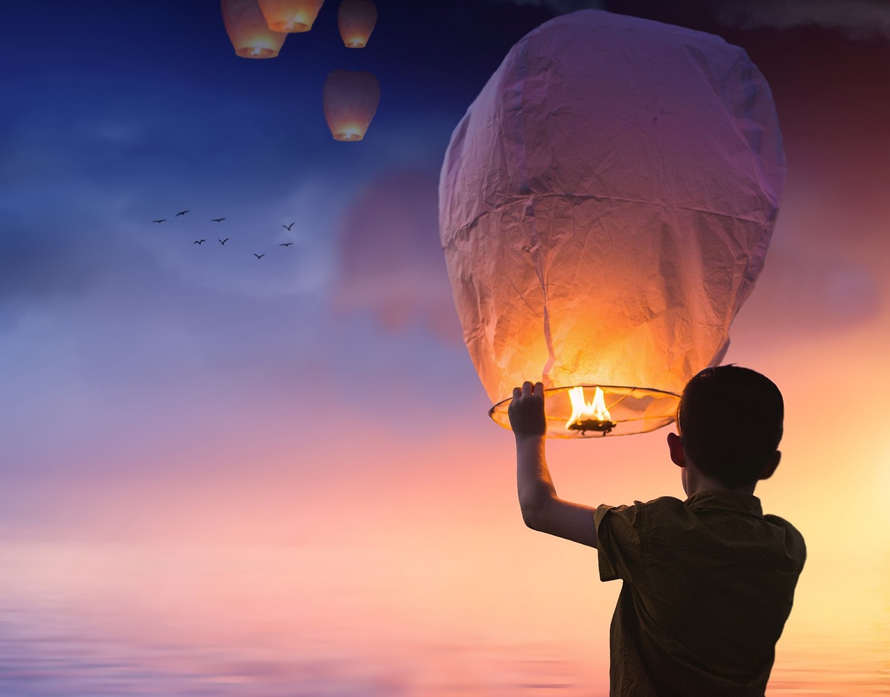 Chłopiec wypuszcza lampion nadziei na niebo, symbolizując przesłanie dla bliskich.