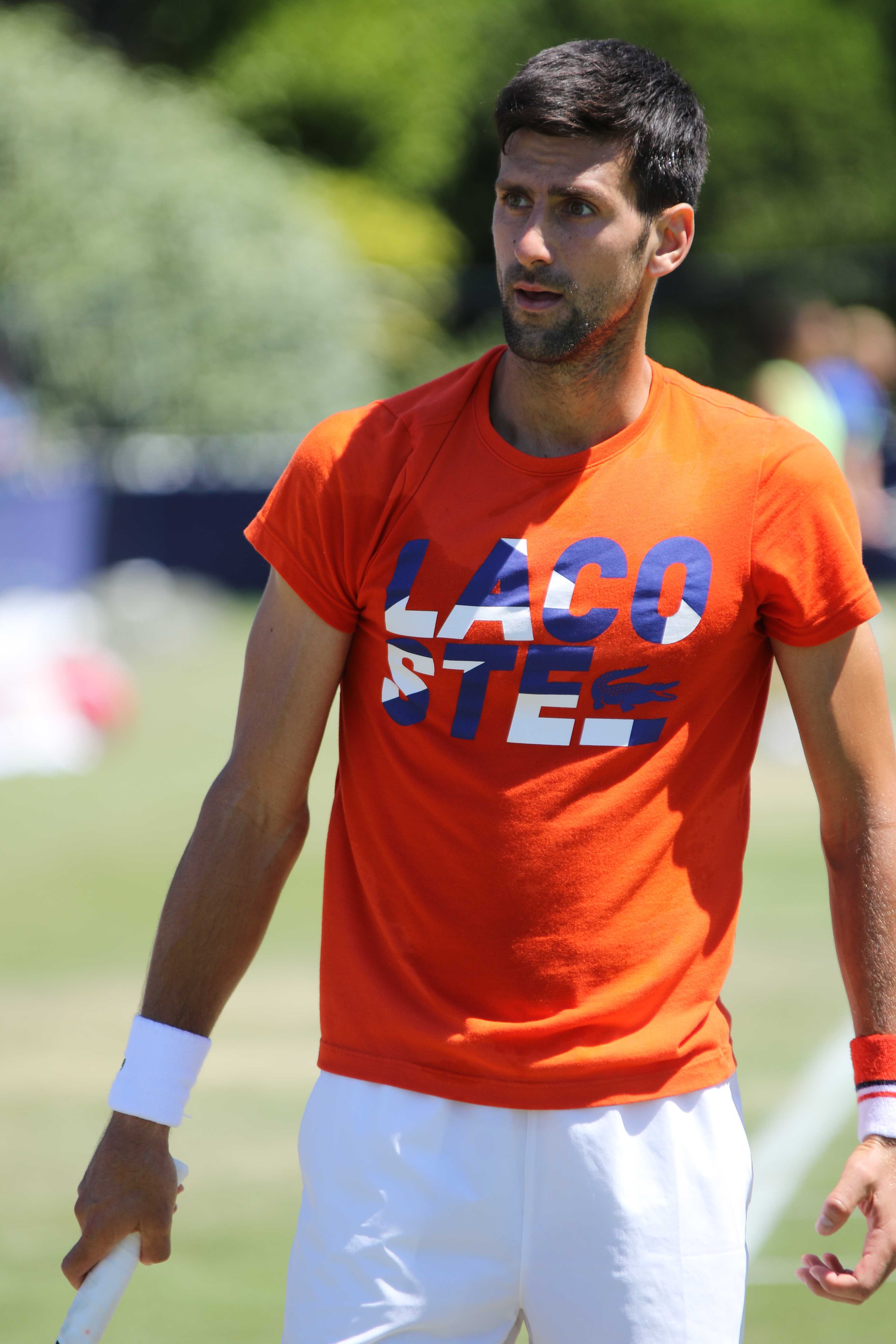 Novak Djoković w pomarańczowej koszulce z logo Lacoste na turnieju w Szanghaju.