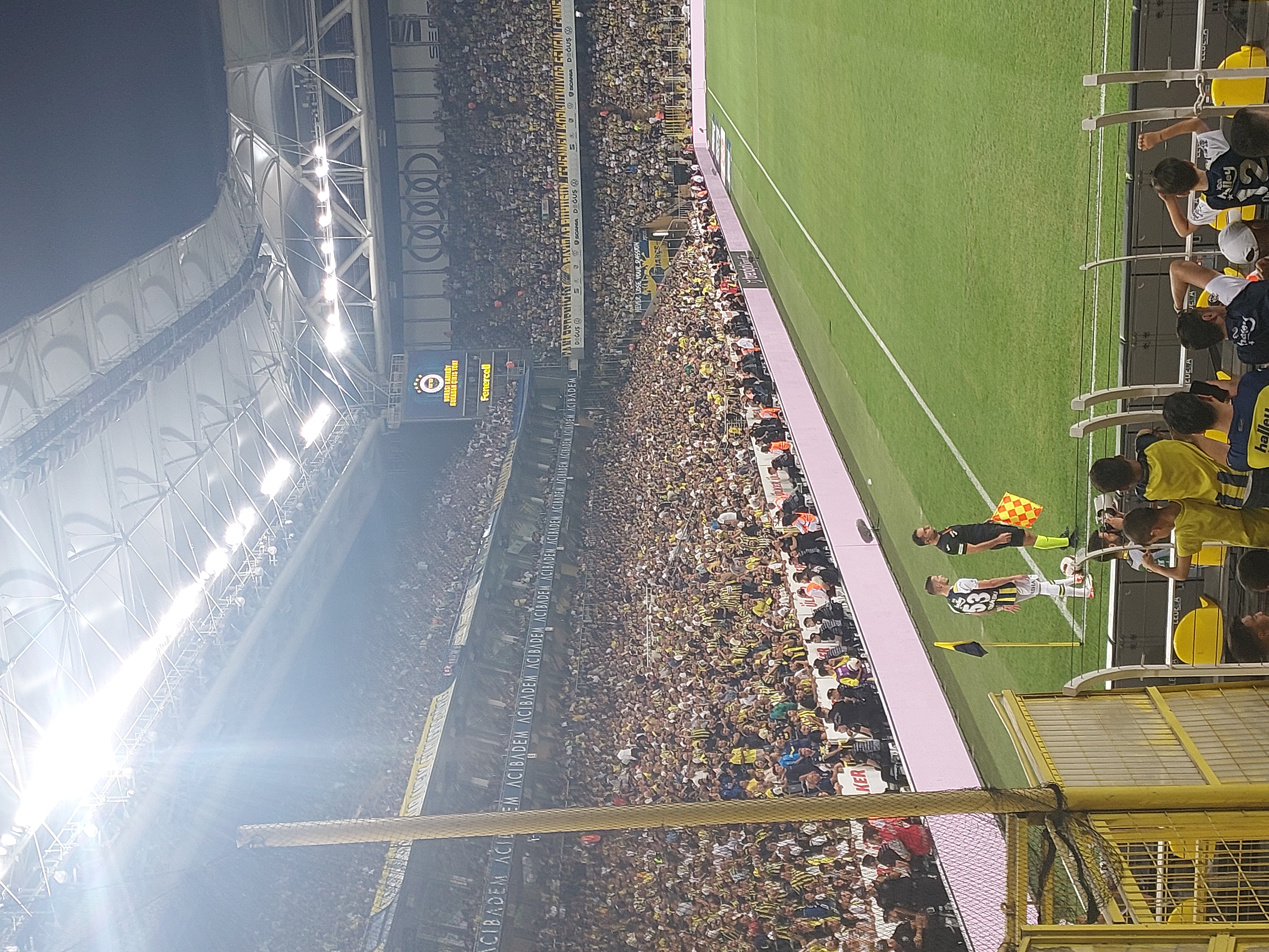 Widok na stadion podczas meczu piłki nożnej, z trybunami wypełnionymi kibicami w żółto-czarnych barwach.