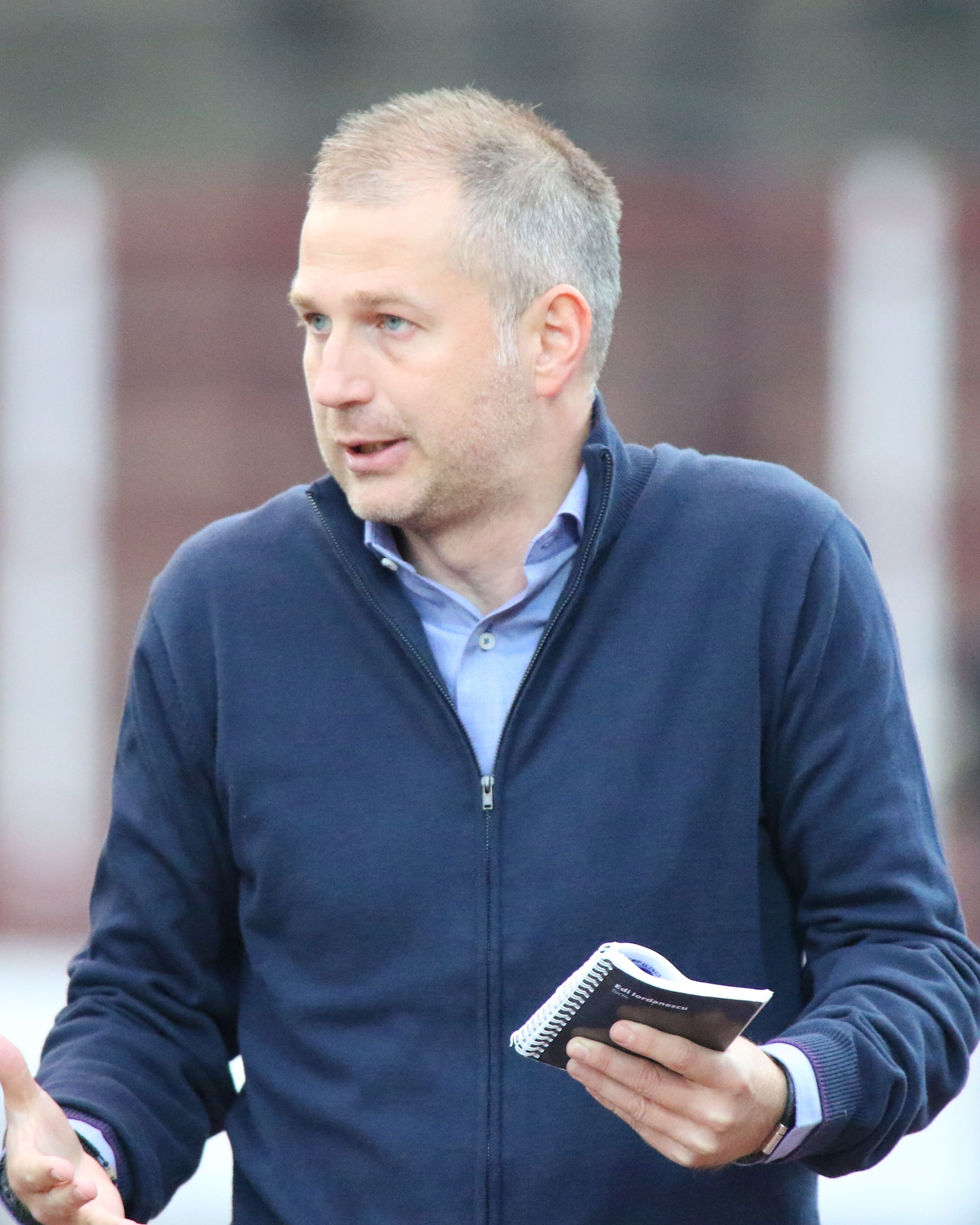Trener Legii Edward Iordanescu z notatnikiem w ręku analizuje taktykę gry.