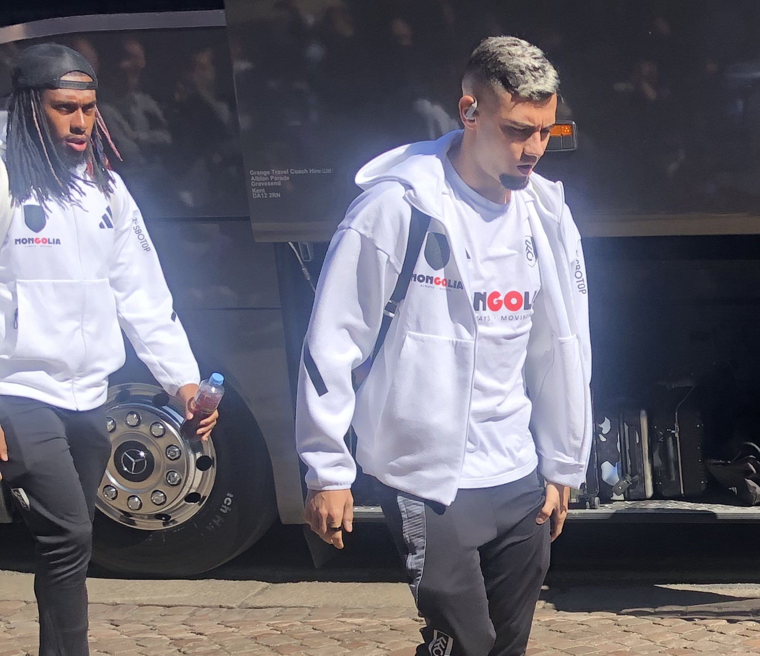 Alex Pereira w białej bluzie przed autobusem, gotowy do walki o pas UFC.
