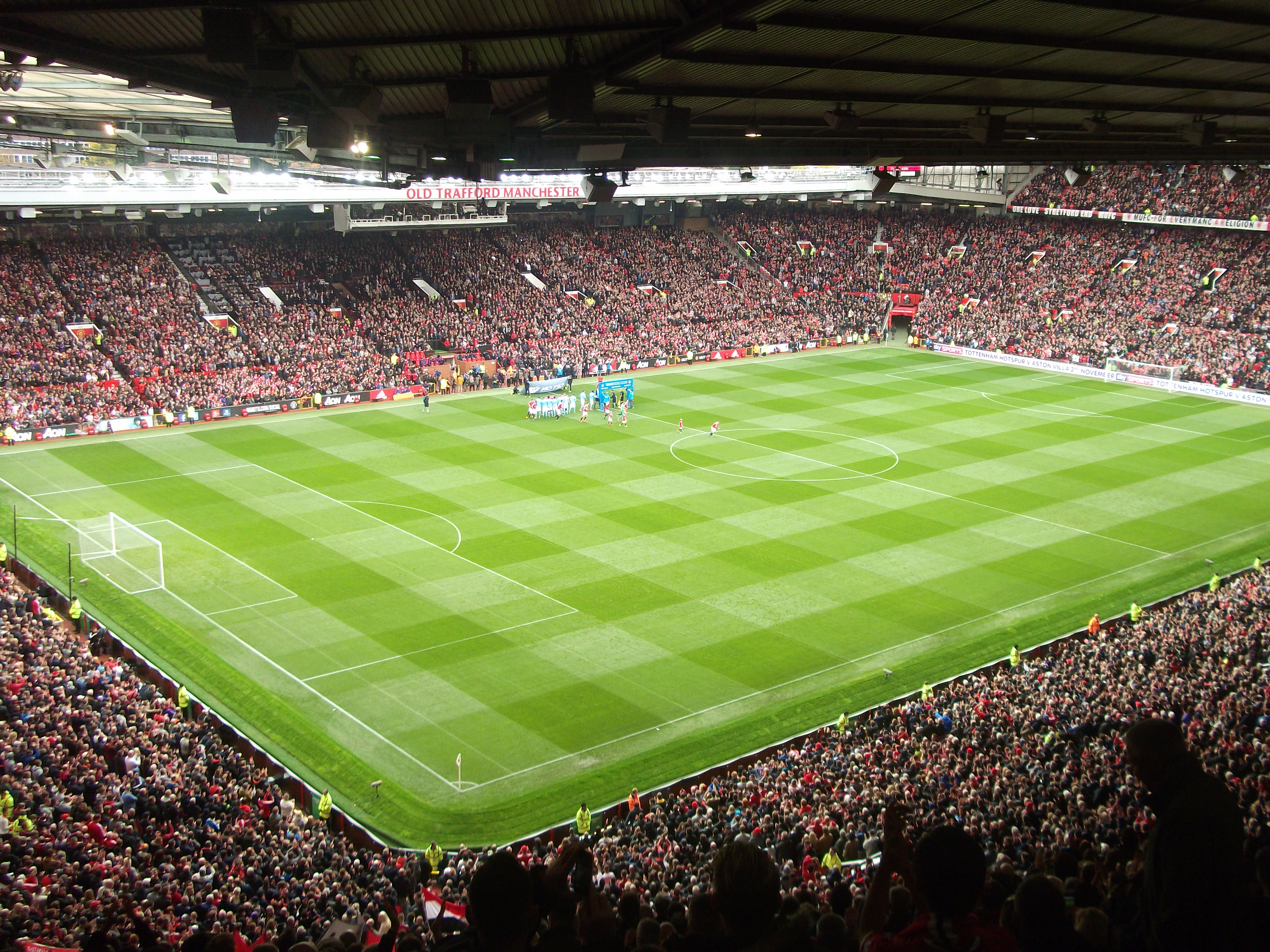 Stadion Old Trafford Manchester United z trybunami wypełnionymi kibicami i murawą.