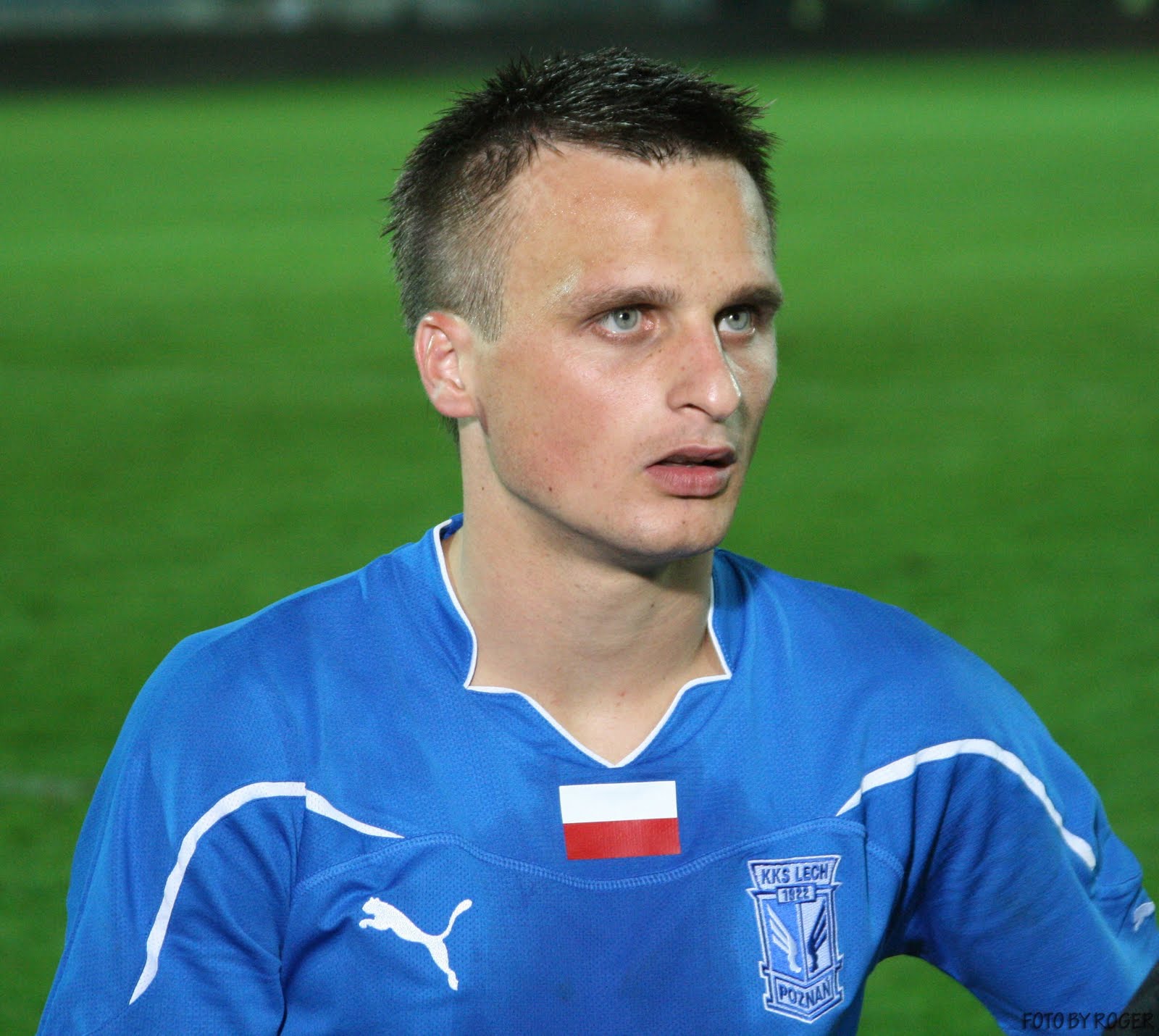Sławomir Peszko w niebieskiej koszulce z godłem KKS Lech Poznań i polską flagą.